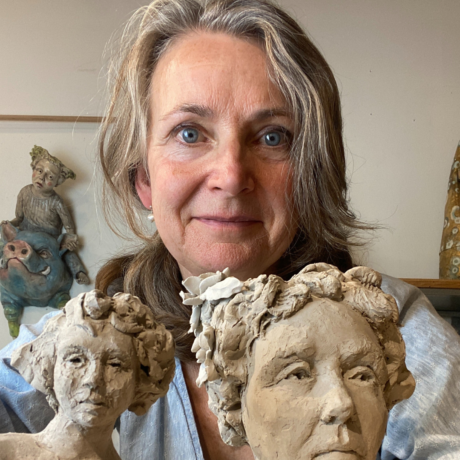 Diane Black Artist Diane Black stands holding two sculptures of women