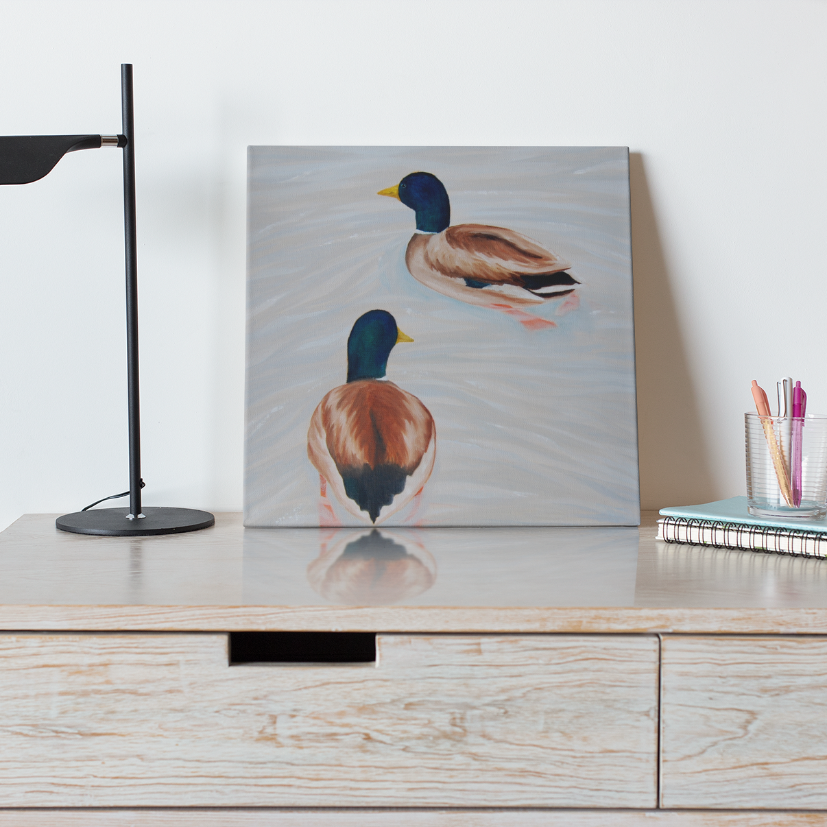 A painting of two ducks by artist Alyssa Sundy sits atop a shelf.